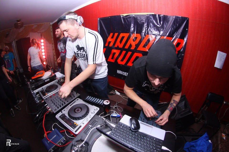 Two DJs performing in front of a Harder & Louder banner